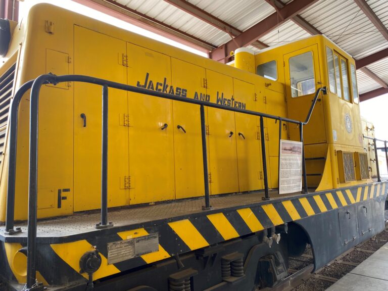 A yellow locomotive with black stripes and black letters.